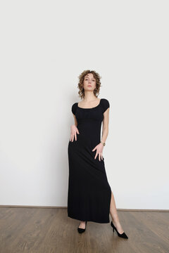 Serie of studio photos of young female model in long elastic black classic and versatile off the shoulder dress 
