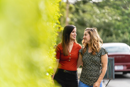 Horizontal Of A Gay Female Couple Walking Very Happily Embracing Outside On A Beautiful Day.