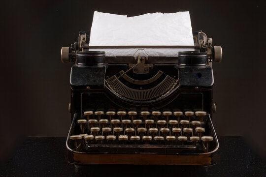 old vintage typewriter isolated on black background with paper sheet