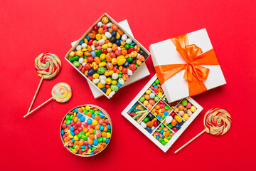 Obraz premium Set of different sweet candy in a paper box with a satin ribbon on a colored background. Holiday concept