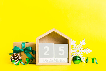 25 december. Christmas composition on colored background with a wooden calendar, with a gift box, toys, bauble copy space