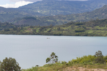 A passanger smal boat sailing into guavio reservoir lake with vig mountain at background