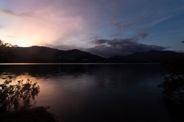 Fototapeta na wymiar Guavio reservoir dam sunset landscape with gachala town mountains silhouette and water silk effect