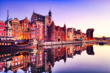 Fototapeta na wymiar Illuminated Gdansk Old Town with Calm Motlawa River at Sunrise, Poland