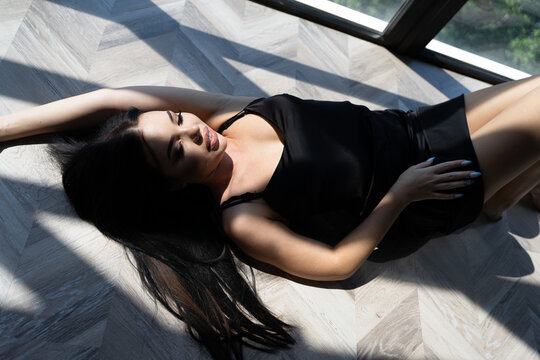 beautiful woman lying on the floor. long haired passion girl in a silk dress