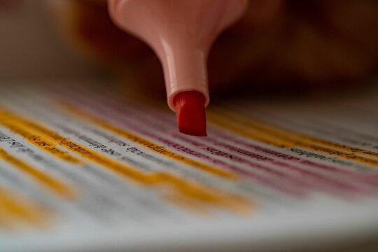 Closeup Shot Of Taking Notes With A Pink Highlighter Pen With The Blurred Background