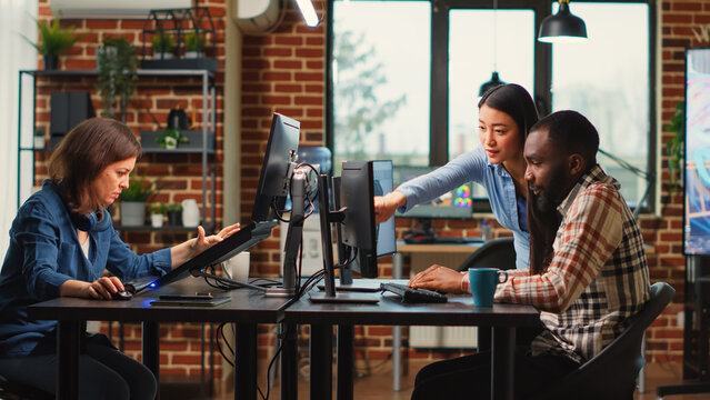 Young team of professional developers using skills to create engineering infographics, using cad software on pc. Diverse colleagues working on creative electronics 3d development.