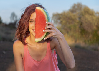 pretty woman shows a watermelon in front of her face demonstrating a healthy lifestyle