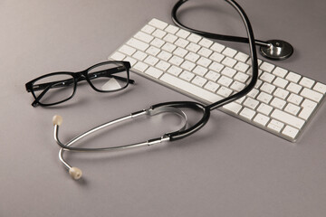 Stethoscope, glasses and keyboard on desktop