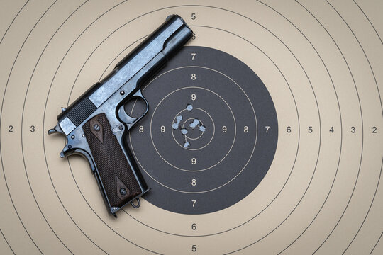 Firearms shooting, model 1911 pistol and target for shooting with bullet holes in the center.