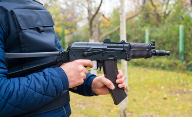 A man holds a Kalashnikov assault rifle in his hands side view