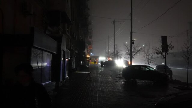 Blackout in the city. No street lightning. Light from cars during fog night.
