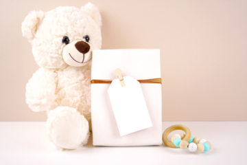 Gift with 2x3.5 thank you favor card tag product mockup. Baby shower 1st birthday christening gender neutral. Styled with white teddy bear against a beige and white background. Negative copy space.