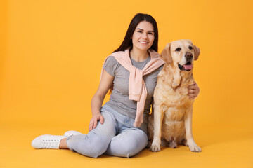 Portrait of happy woman with cute Labrador Retriever on orange background