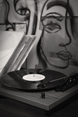 Stylish turntable with vinyl disc on table in room, closeup. Black white filter