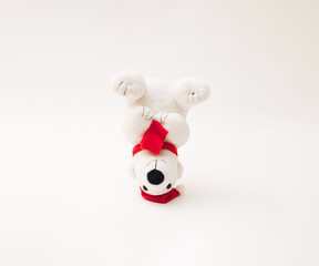 Upside down plush toy polar bear with red Santa Claus hat and scarf.