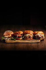 4 types of burgers on a wooden board