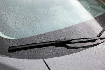 Car wiper cleaning water drops from windshield glass, closeup - obrazy, fototapety, plakaty