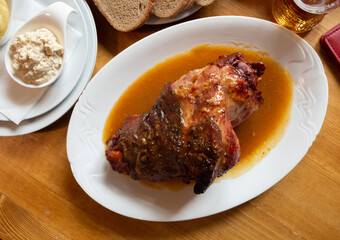 Top view of baked pork knuckle traditionally served in gravy with horseradish, mustard and fresh bread. Traditional czech cuisine