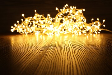 Beautiful glowing Christmas lights on wooden table. Space for text