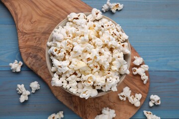 Tasty popcorn on light blue wooden table, flat lay