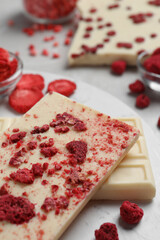 Chocolate bars with freeze dried raspberries on light marble table, closeup