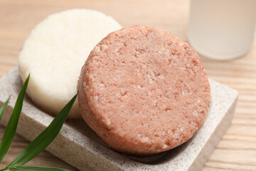 Dish with solid shampoo bars on wooden table, closeup