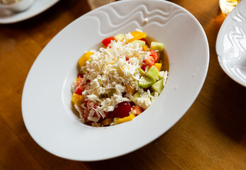 Dish of Balkan cuisine Shopska salad with cucumbers, tomatoes, bell peppers and brynza (salted sheep cheese)