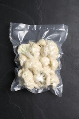 Vacuum pack of cauliflower on dark grey table, top view
