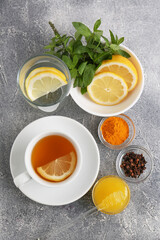 Obraz na płótnie Canvas Cup with delicious immunity boosting tea and ingredients on grey table, flat lay