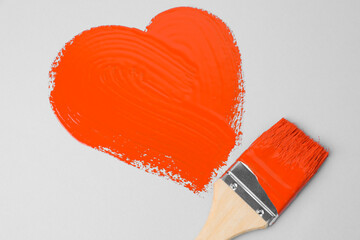 Heart shape made with orange paint and brush on white background