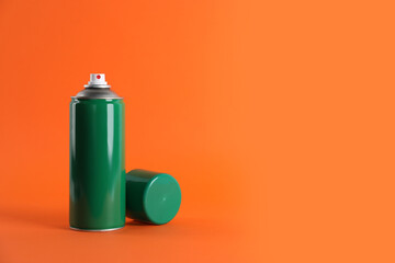 Green can of spray paint on orange background. Space for text