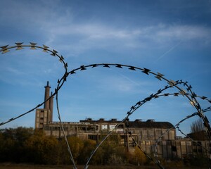 Closeup shot of barbwire with a blurred old chemical plant in Brandenburg, Germany