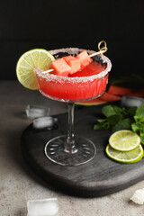 Cocktail glass of delicious fresh watermelon juice, lime, mint and ice on grey table
