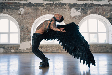 handsome man with wings.Male angel with black wings.  Muscular shirtless man with whip. Brutal handsome man with tattooed body. Muscular athletic sexy male  - obrazy, fototapety, plakaty