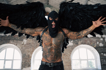 Male angel with black wings. Black angel in a mask. Muscular shirtless man with whip in a mask.Brutal handsome man with tattooed body. Muscular athletic sexy male with naked torso. hot man