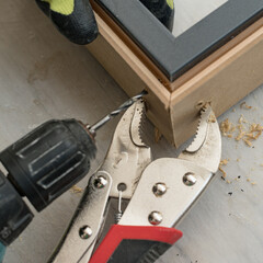 Obraz premium The craftsman drills the door for connection at the corner, the clamps hold the two slats of the door.