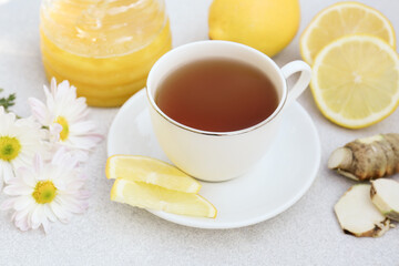 Cup of delicious tea with honey, lemon and ginger on white table