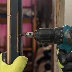 The craftsman drills a hole in the door frame for subsequent attachment to the wall.