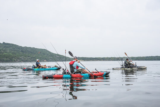 Three men kayak anglers paddling on a Texas lake