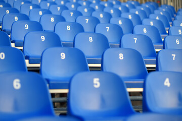 View of empty seats with numbers in the stands. Arena stands are waiting for crowds of fans. Theater, concert hall, audience are ready to start of the performance, lecture or conference.