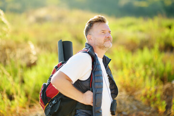 Obraz premium Mature man hiking on sunny summer day. Adventure concept. Solo travel. Hitch-hiking. Backpacking trip