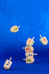 Obraz premium Jewish holiday Hanukkah concept. Wooden dreidel (spinning top) levitation on blue background.