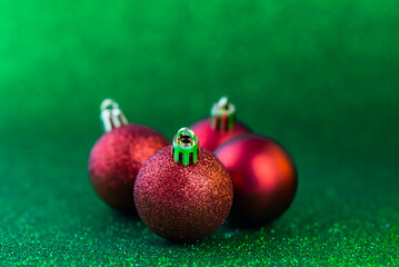 Christmas and new year decorations. Red baubles on green sparkle glitter background.