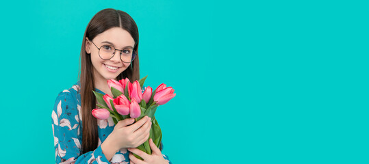 kid hold flowers for 8 of march. teen girl with spring bouquet on blue background. Banner of spring child girl with tulips flowers bouquet, studio portrait with copy space.