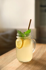 Delicious lemonade with mint in mason jar on wooden table indoors. Refreshing drink