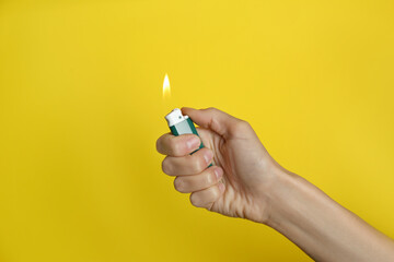 Woman holding green lighter on yellow background, closeup