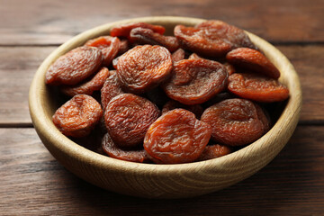 Bowl of tasty apricots on wooden table, closeup. Dried fruits