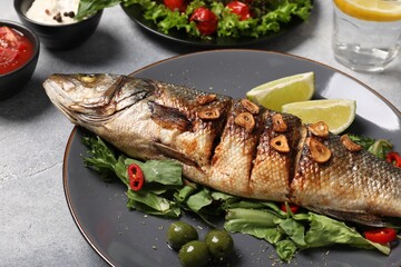 Delicious sea bass fish and ingredients on light grey table, closeup