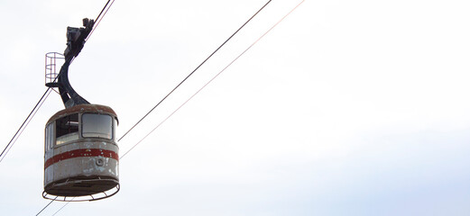 Horizontal banner. Vintage old cabin of an abandoned cable car in the Georgian city of Tbilisi against a light sky. The concept of abandonment, old age. Tourist route, journey, vacation, vacation